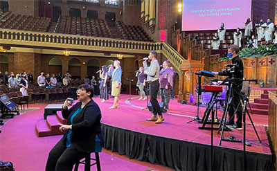 The worship team and choir during a service at The Moody Church. The frontline singers and leader Tim Stafford, pastor of music ministries, on guitar, all use ASI Audio 3DME active ambient IEMs.